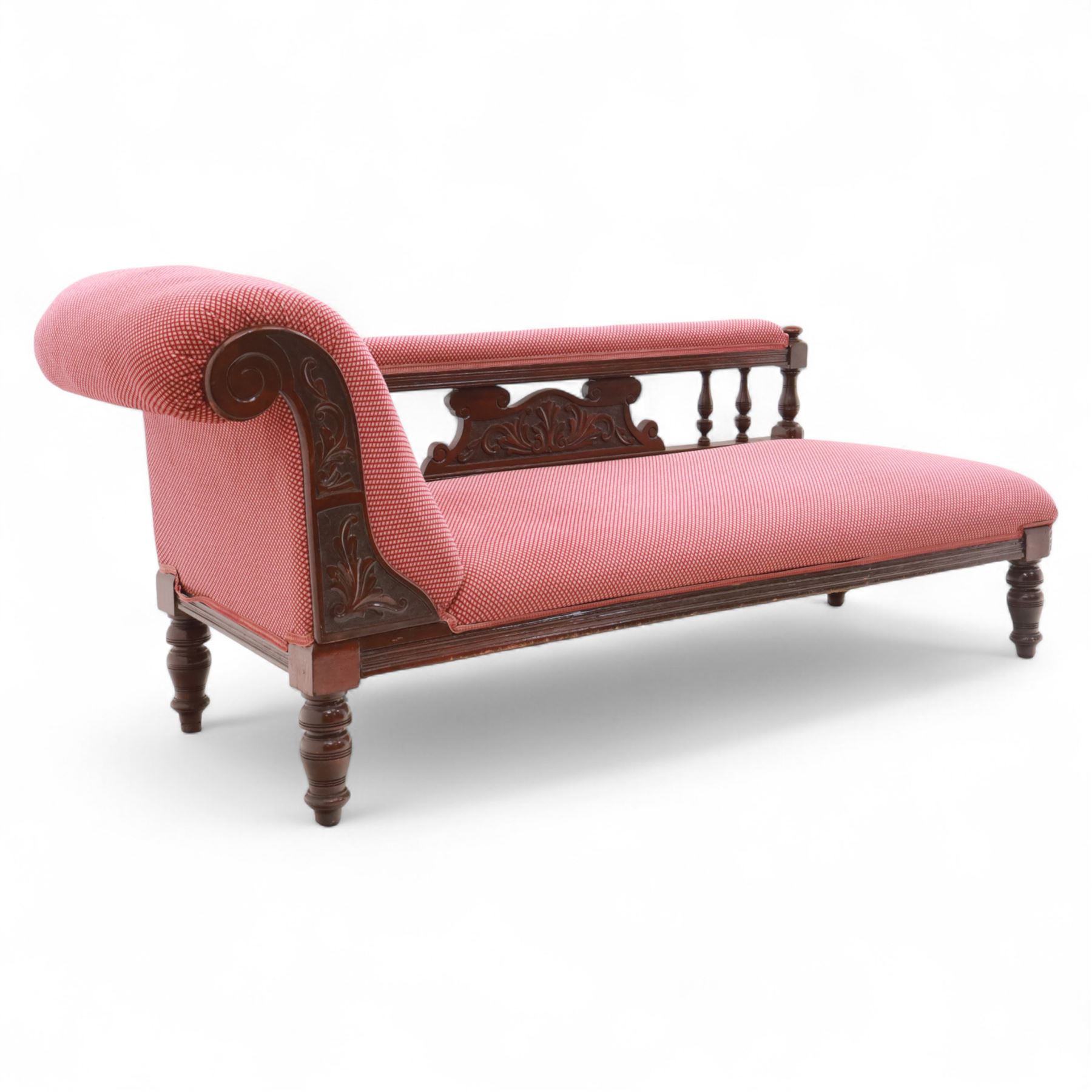 Late Victorian mahogany chaise longue, of scroll-ended form, upholstered in red diamond-patterned fabric with padded back and scroll-carved support, open arm with carved foliate and turned upright, raised on turned tapering legs 