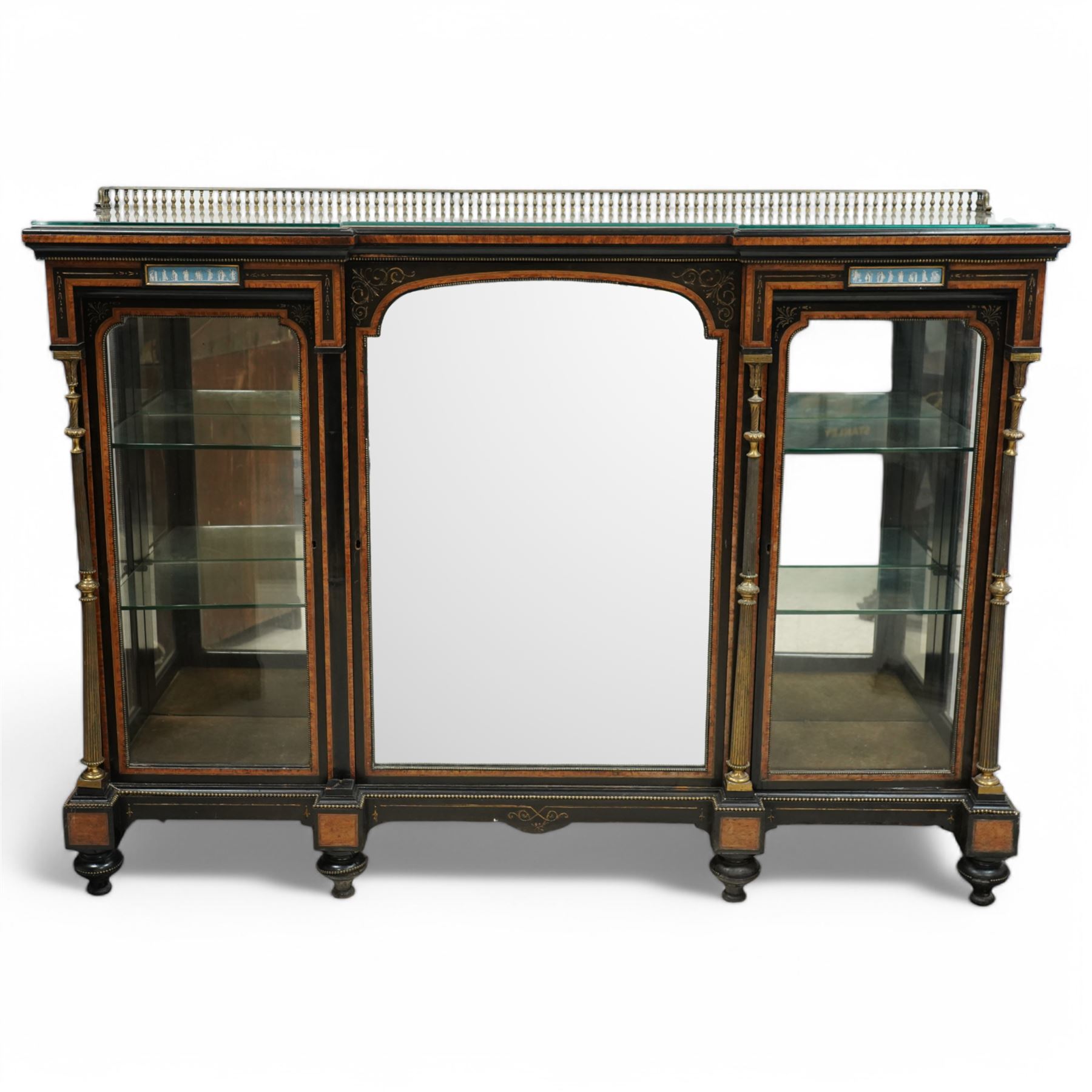 Victorian amboyna and ebonised credenza with glass top, the freeze fitted with two Wedgewood plaques and brass beading above crossbanded arched glazed mirror door flanked by two glazed cabinet doors with two removable glass shelves between four gilt brass reeded floral columns, supported on bun style feet
