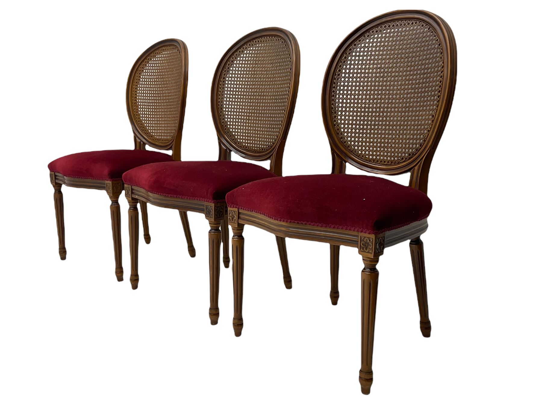 Set six French style walnut finish dining chairs, oval cane bergere backs over serpentine seats upholstered in red, flower head carved fluted supports