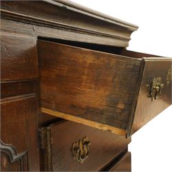 19th century Georgian oak long dresser base, rectangular plank top above a central frieze drawer over a fielded panel cupboard, flanked by three banks with quarter cantered pilasters, brass swan neck handles and escutcheons, raised on shaped bracket feet