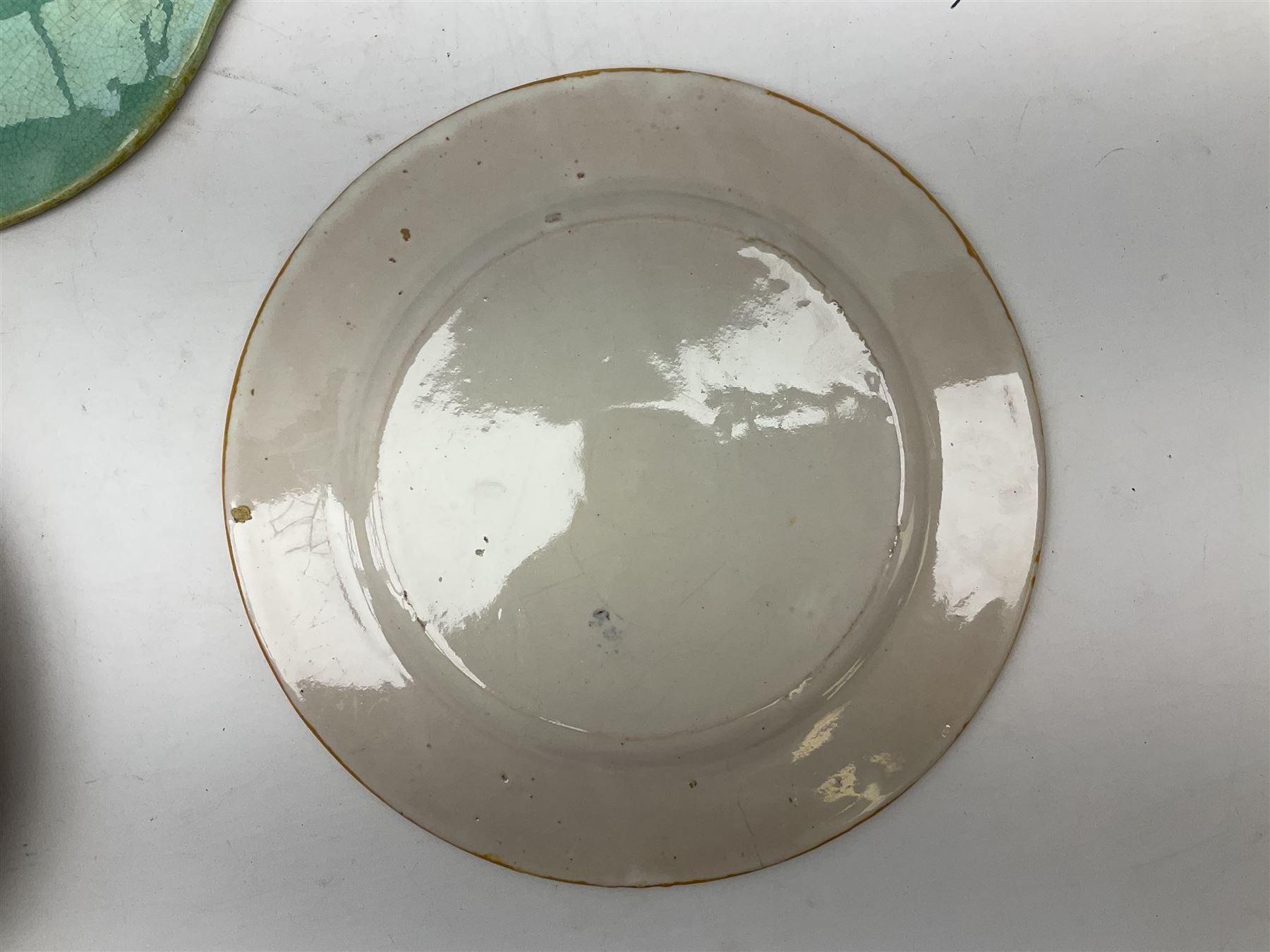 Majolica plate decorated with yellow and brown bird upon fruiting holly branches on teal ground with mustard rope twist border, together with two other plates to include a Faience style example, D27cm