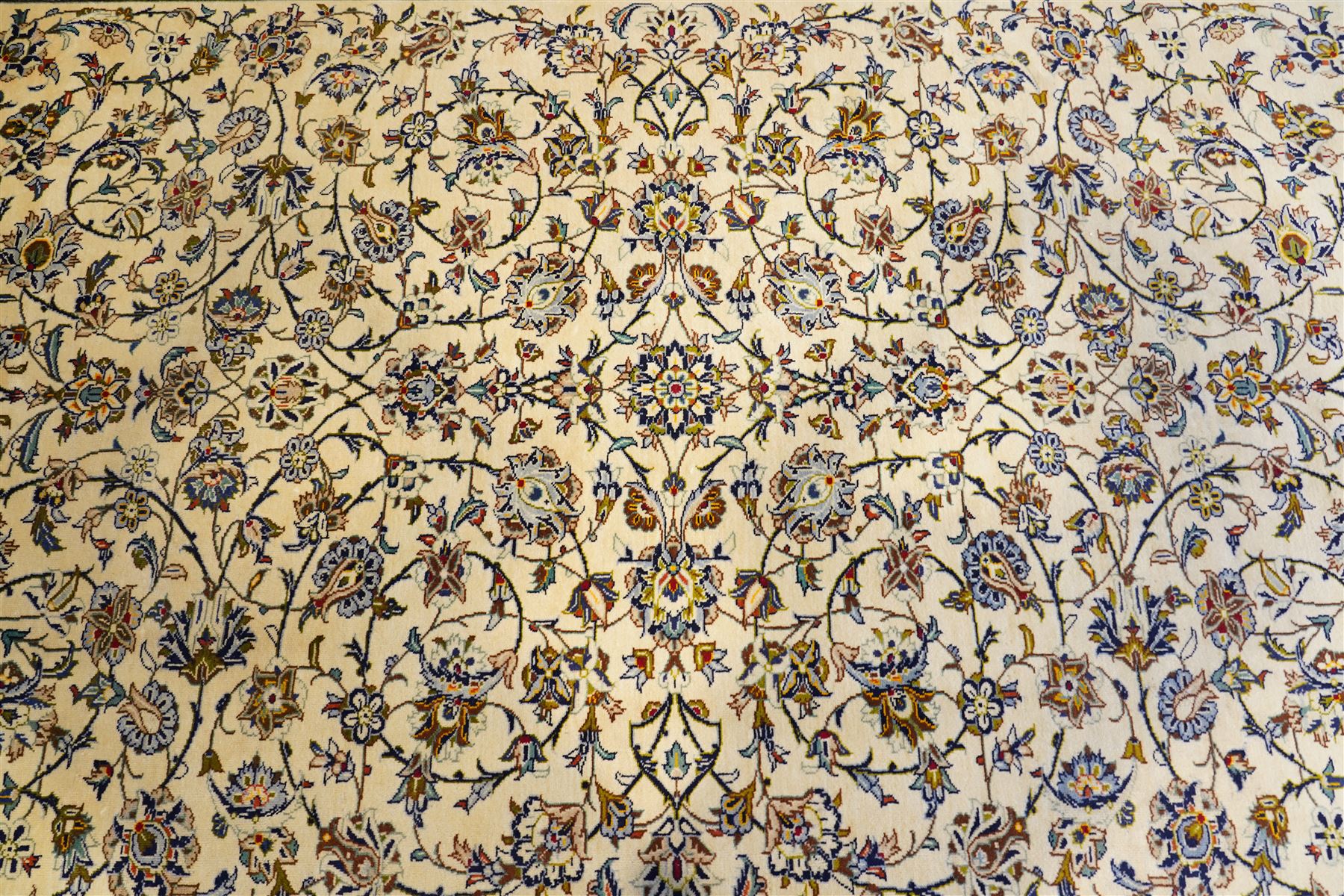 Central Persian Kashan hand-knotted carpet, ivory field decorated with an all-over scrolling floral vine design incorporating stylized palmettes, rosettes, and foliate sprays in the Shah-Abassi style enclosed by a series of floral vine borders and multiple narrow guard stripes, cotton fringe ends 