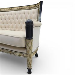 20th century Louis XVI style settee, upholstered in cream fabric with buttoned back and arms, and plain seat cushions, the shaped and black painted frame with entwined foliate detail and gilt flower heads, upon column legs with bun feet