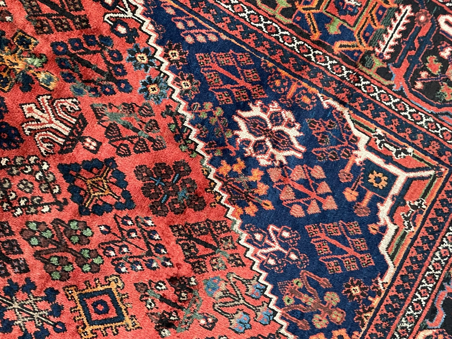 Persian Joshgan red ground rug, the medallion, field and spandrels decorated with clusters of Pitrak and tree of life motifs, the border with repeating design decorated with stylised plant motifs, within guard stripes