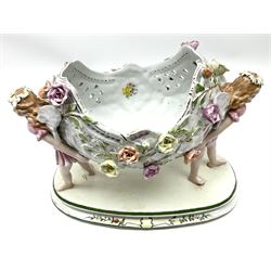 Continental ceramic centrepiece, in the style of Dresden, decorated with two fairies holding up an oval bowl with floral detail, with spurious blue crossed swords beneath, H26cm.    