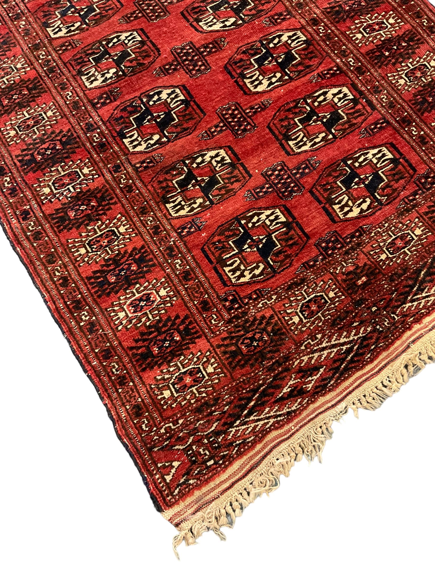 Bokhara red ground rug, decorated with two rows of Gul motifs, the border with geometric guard bands decorated with stylised plant motifs