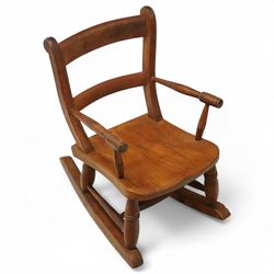 Early 20th century pine child’s rocking chair, with curved top rail over a shaped solid se...