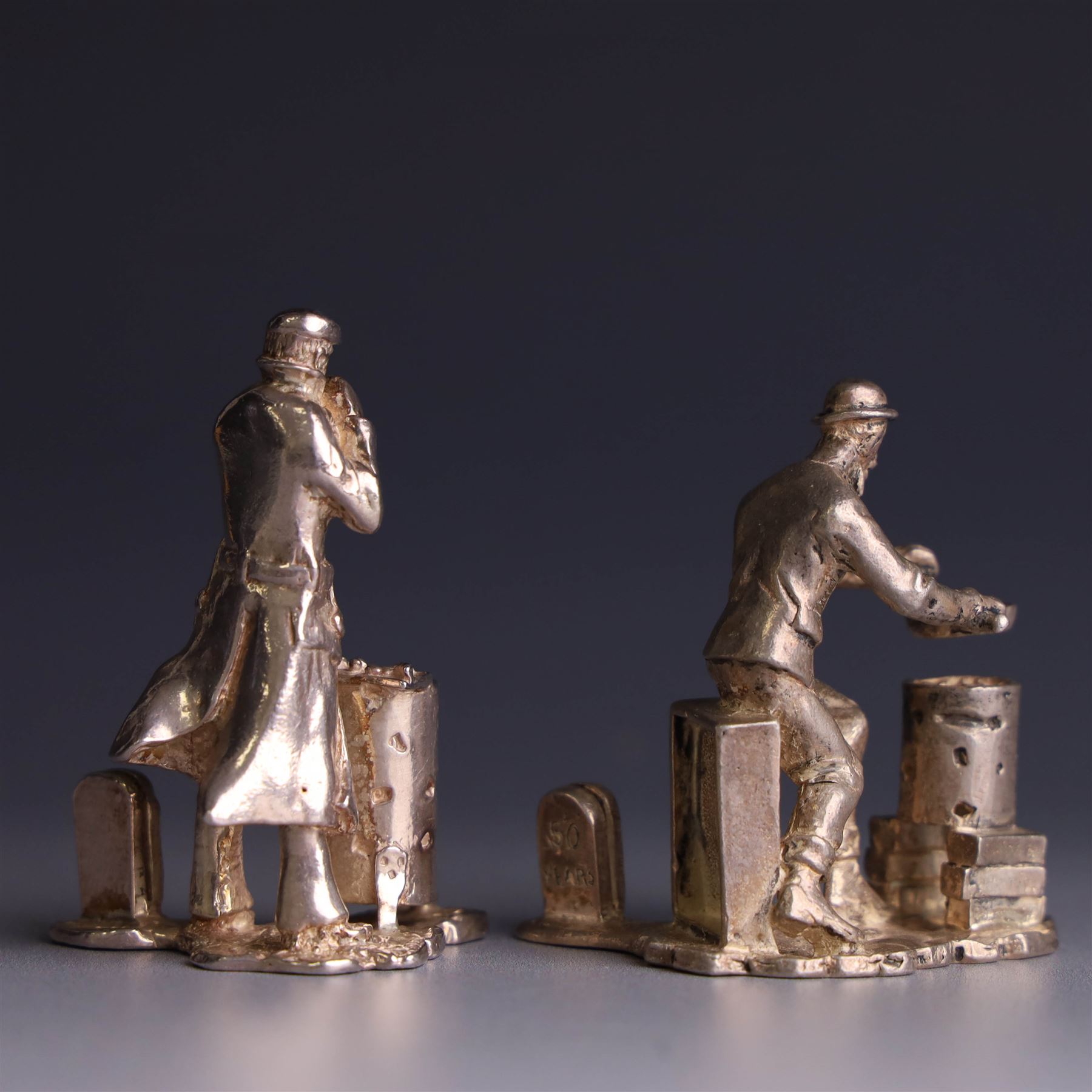 Two silver place card holders from the 'Cries of London' series, each depicting traditional London street traders, hallmarked Thomas Charles Jarvis, London 2000, tallest H5cm