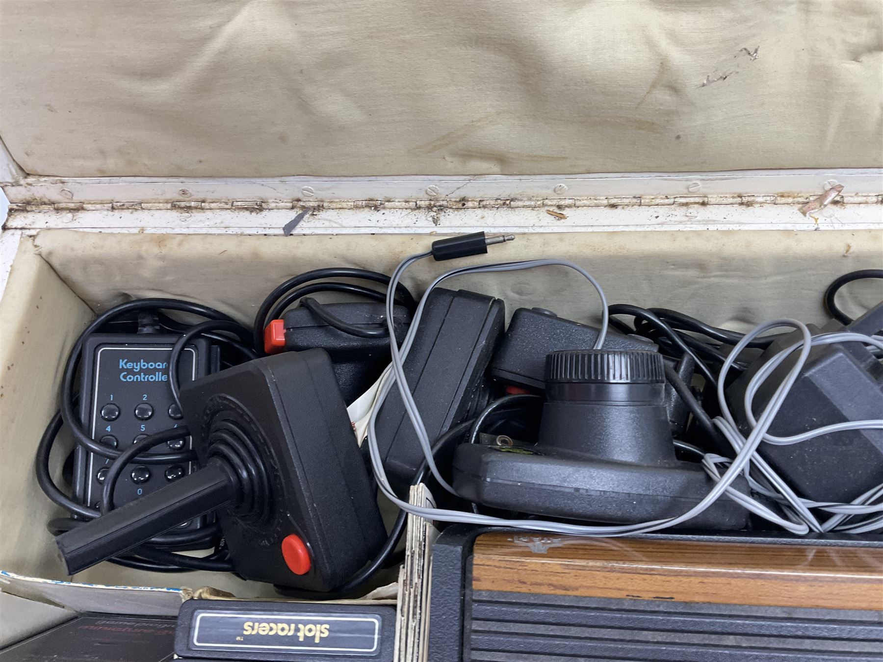 Atari 2600 'Woody' console with various joysticks and controllers etc, and a quantity of game cassettes to include 'Outlaw', 'Air Sea Seattle' and 'Codebreaker' etc housed in white painted wood case