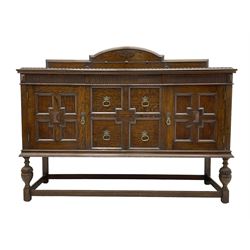 Early 20th century oak sideboard, raised stepped arch back over moulded rectangular top, fitted with two drawers and two panelled cupboards with geometric mouldings, on turned and lobe carved baluster feet united by stretchers 