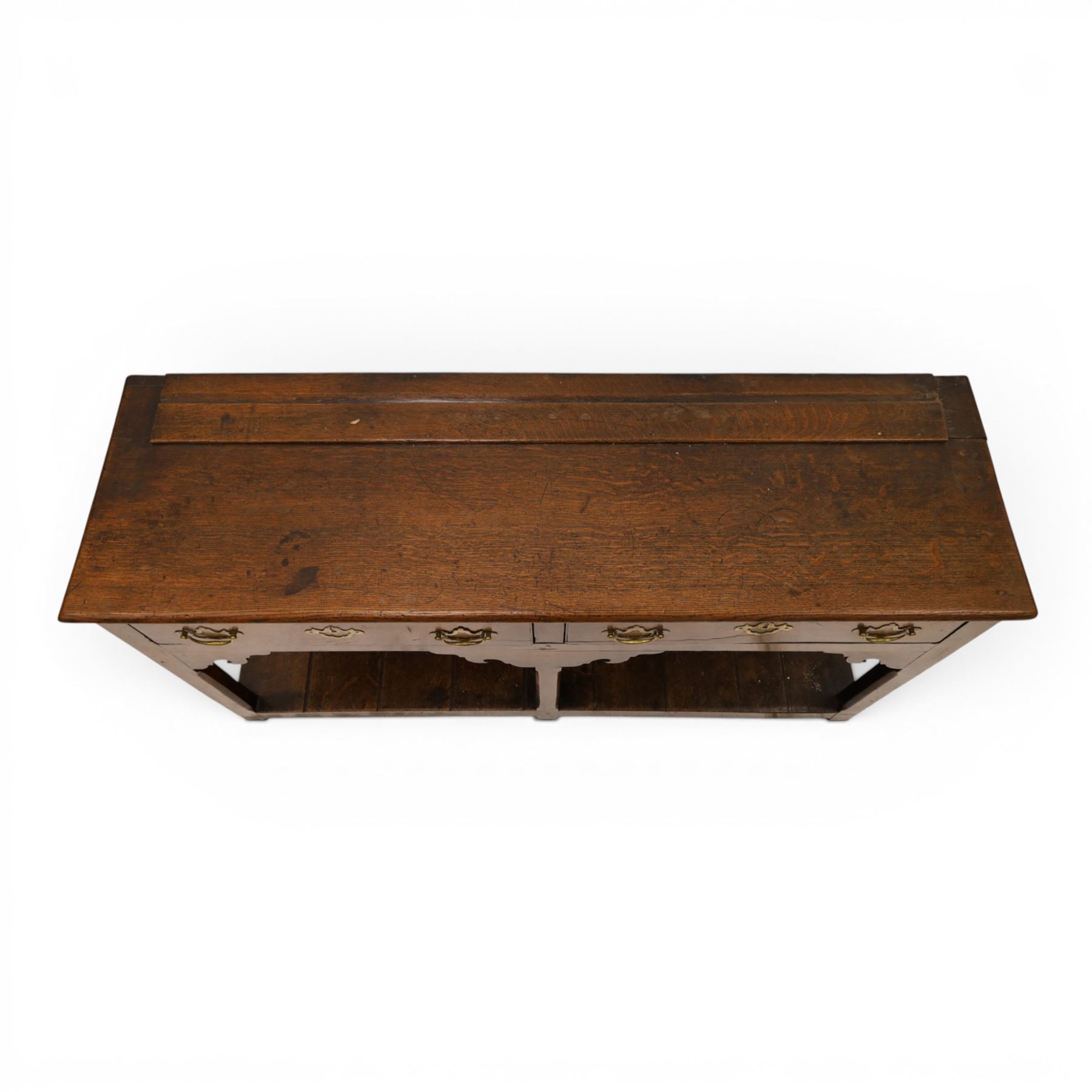 George III oak dresser base, rectangular top with moulded edge, fitted with two drawers over shaped spandrels, raised on square chamfered supports united by undertier, on stile feet