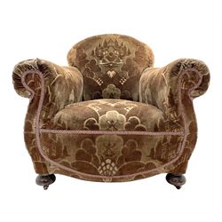 Late 19th century armchair of generous proportions, traditional shaped frame, sprung seat and back, on turned bun feet with castors, upholstered in green and brown patterned fabric depicting mountains and windmills