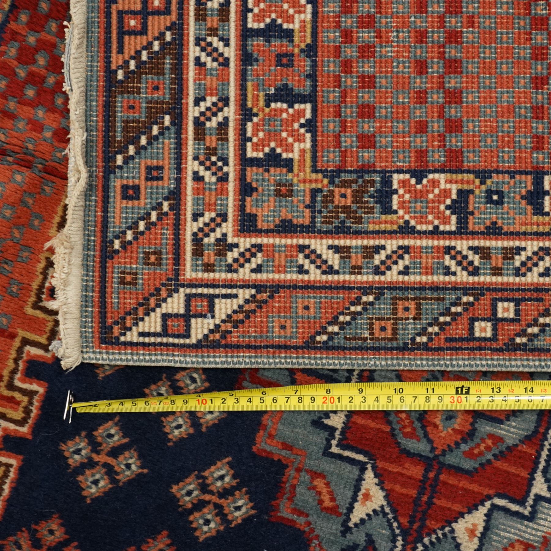 North West Persian Heriz hand-knotted rug, indigo field with three central stepped geometric medallions arranged vertically, enclosed by angular spandrels and multiple geometric borders in shades of madder red, ivory, and pale blue, with cotton fringe ends  