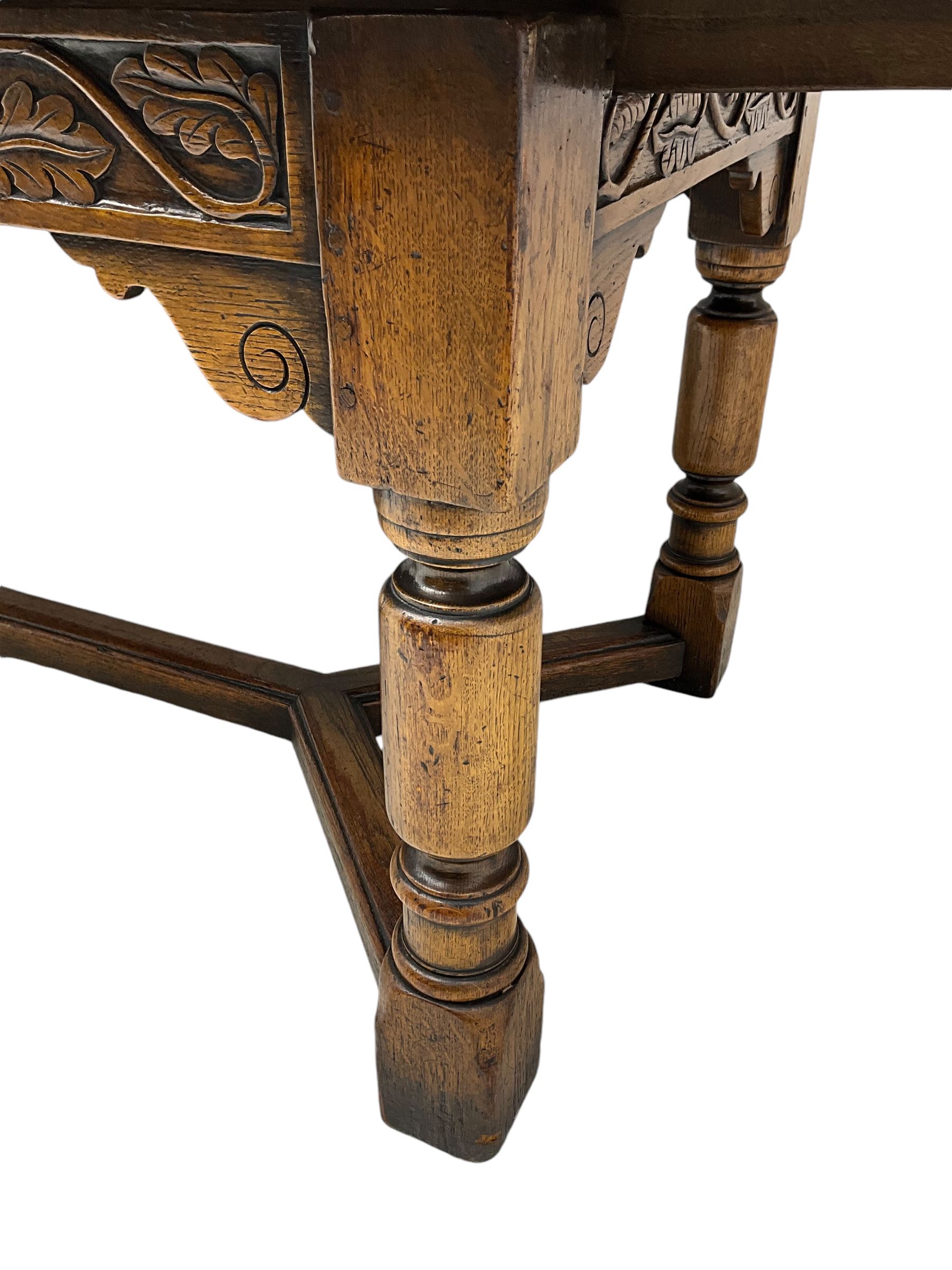 Early 20th century Jacobean design draw-leaf oak dining table, rectangular top with carved frieze depicting scrolling foliage and grape clusters, sliding extending leaves, raised on robust turned supports united by H-stretcher  