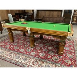 Late 20th century oak slate bed billiard table, on six turned column supports,  together with cues, ball set, baize brush, triangles and scoreboard 