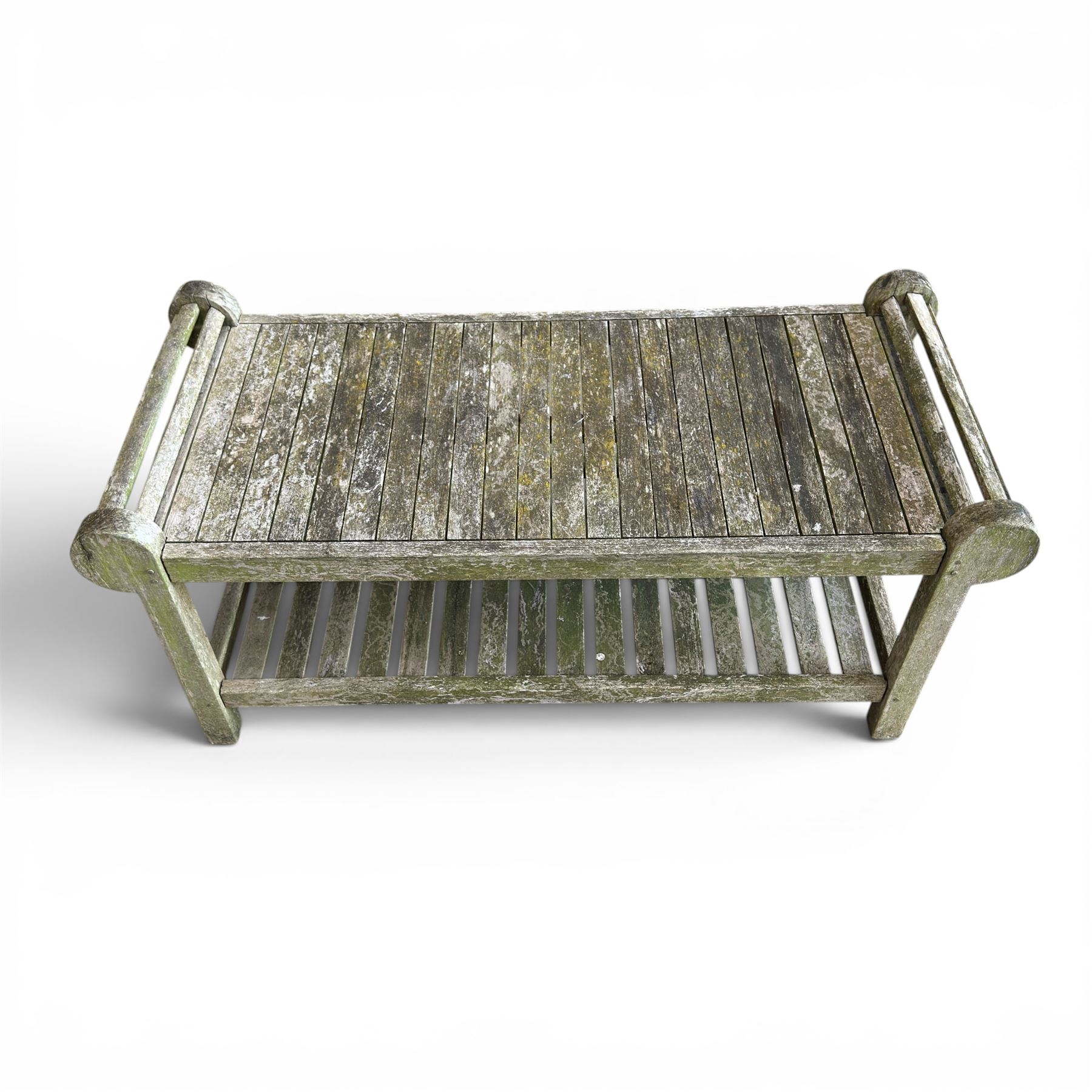 Lutyens design weathered teak garden bench with matching two-tier table, the bench with shaped arched and slatted back over rolled arms and slatted seat