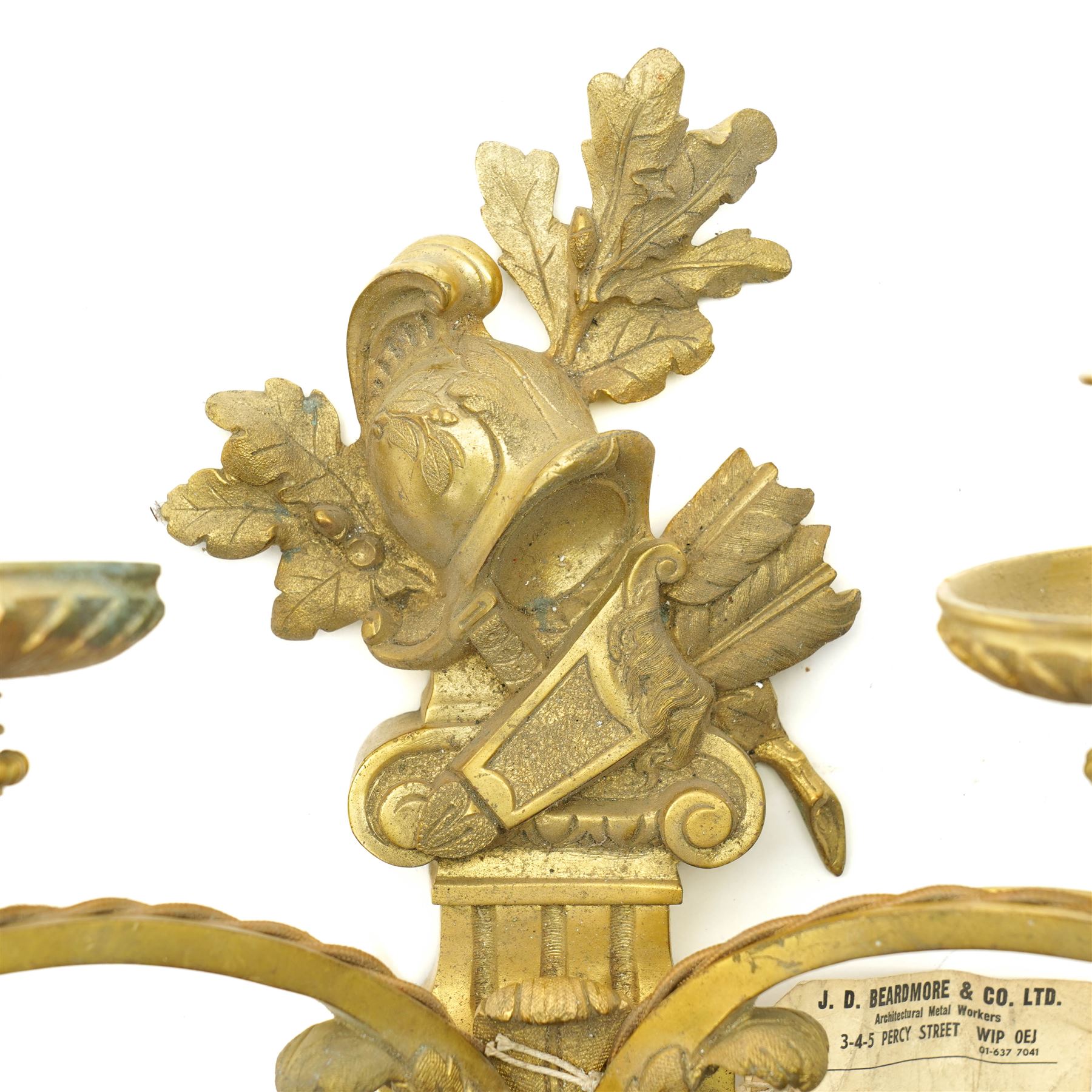 Period design gilt brass wall light, by Beardmore, London, with French empire motifs, including a helmet, oak leaves and acorns, quiver, each arm with acanthus leaf decoration, wired for electricity, with original label, H36cm  
Provenance: property of a Nobleman