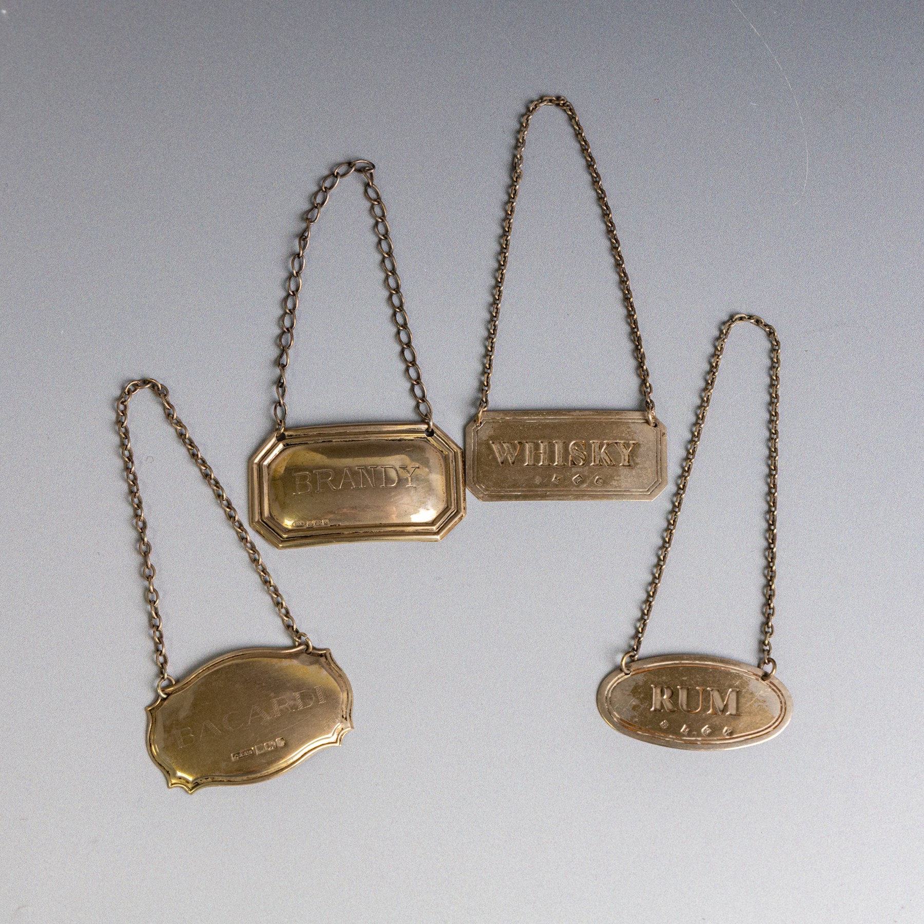 Five silver decanter labels, of varying design, including Bacardi, Vodka, Rum, Brandy and Whisky, all hallmarked together with two silver plated Gin and Sherry examples