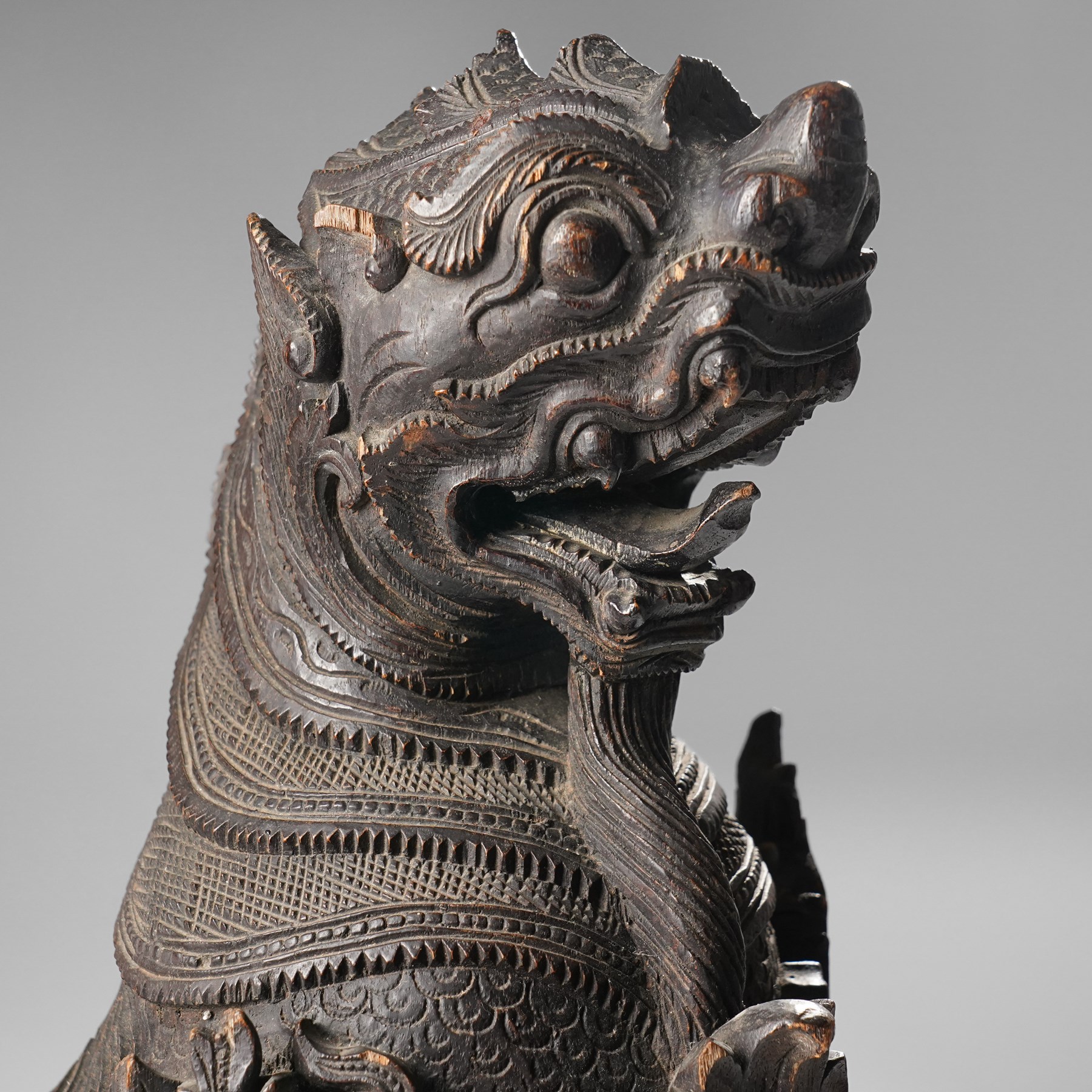 Burmese carved temple guardian figure, depicted seated with carved flame details, H52cm 
