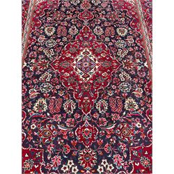 Persian indigo ground rug, the central crimson pole lozenge medallion surrounded by interlacing floral patterns, the main border with repeating plant motifs connected by scrolling branches