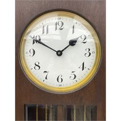 A mid-20th century weight driven floor standing clock in an oak case with canted glazed panels, full length glazed trunk door on a rectangular plinth with applied double skirting, white enamel dial with a gilt slip, upright Arabic’ numerals, minute markers, quarter hour Arabic’s and steel spade hands, with a three-train weight driven Westminster chiming movement chiming on two sets of gong rods.
With pendulum and weights.

