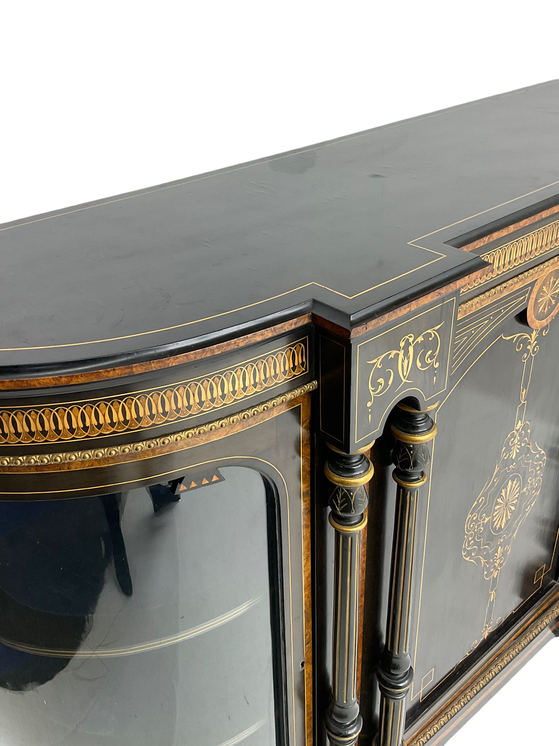 Victorian ebonised and inlaid credenza, break-front with curved ends, the front fitted with two curved glazed doors and central panelled door, inlaid with scrolling foliate and star motifs, quadruple turned and fluted pilasters to front, gilt egg and dart moulded edge on plinth base with figured walnut band, on turned feet