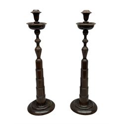 Pair of turned wooden candlesticks, the central column of stepped form raised upon circular spreading base, with drip trays, H56cm
