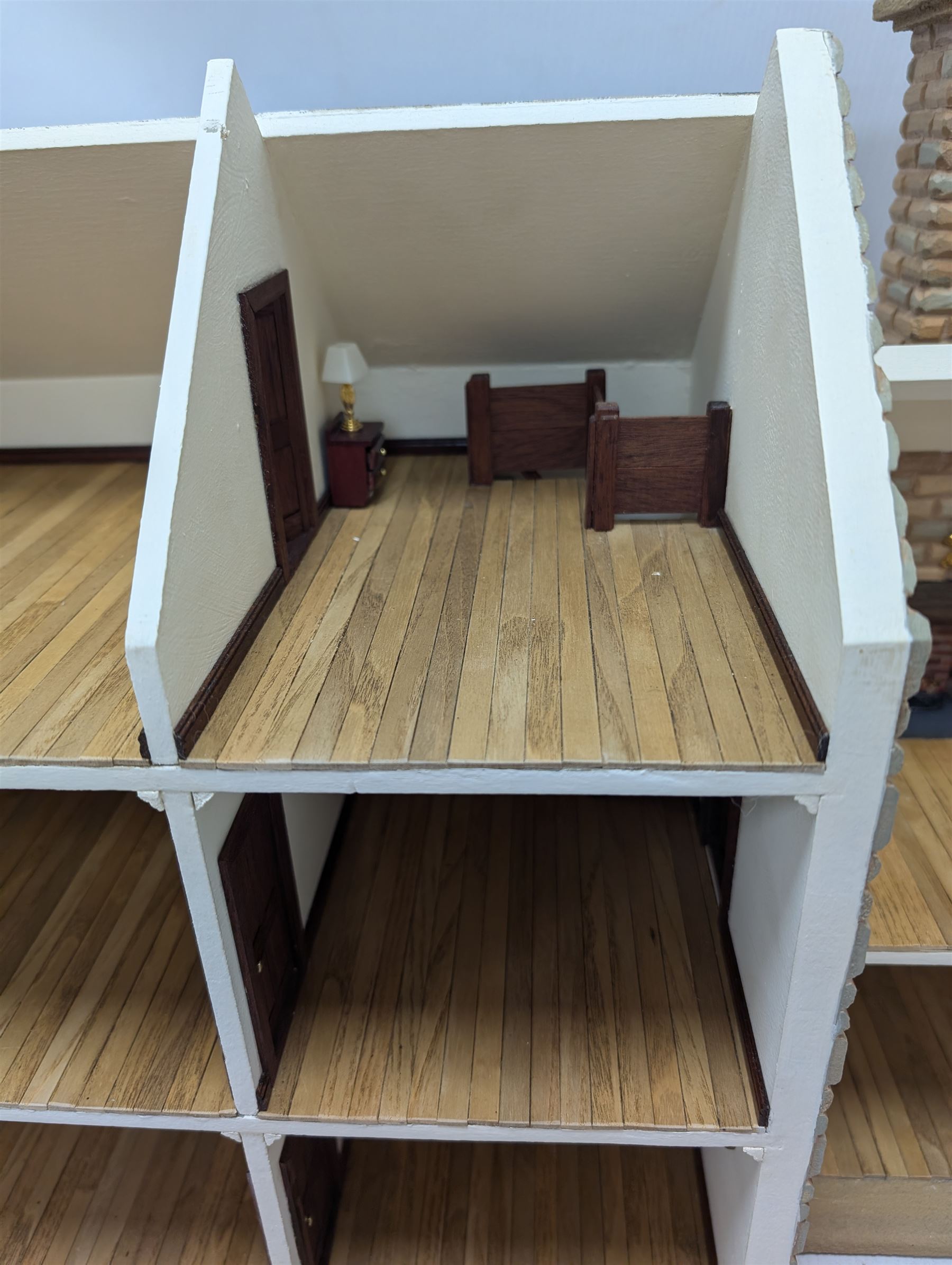 1:24 scale stone effect three-storey cottage dolls house, with green arched door and lattice effect windows, decorated to the interior with wooden floors, wired lighting and fire places, H45cm, W57cm, D26cm