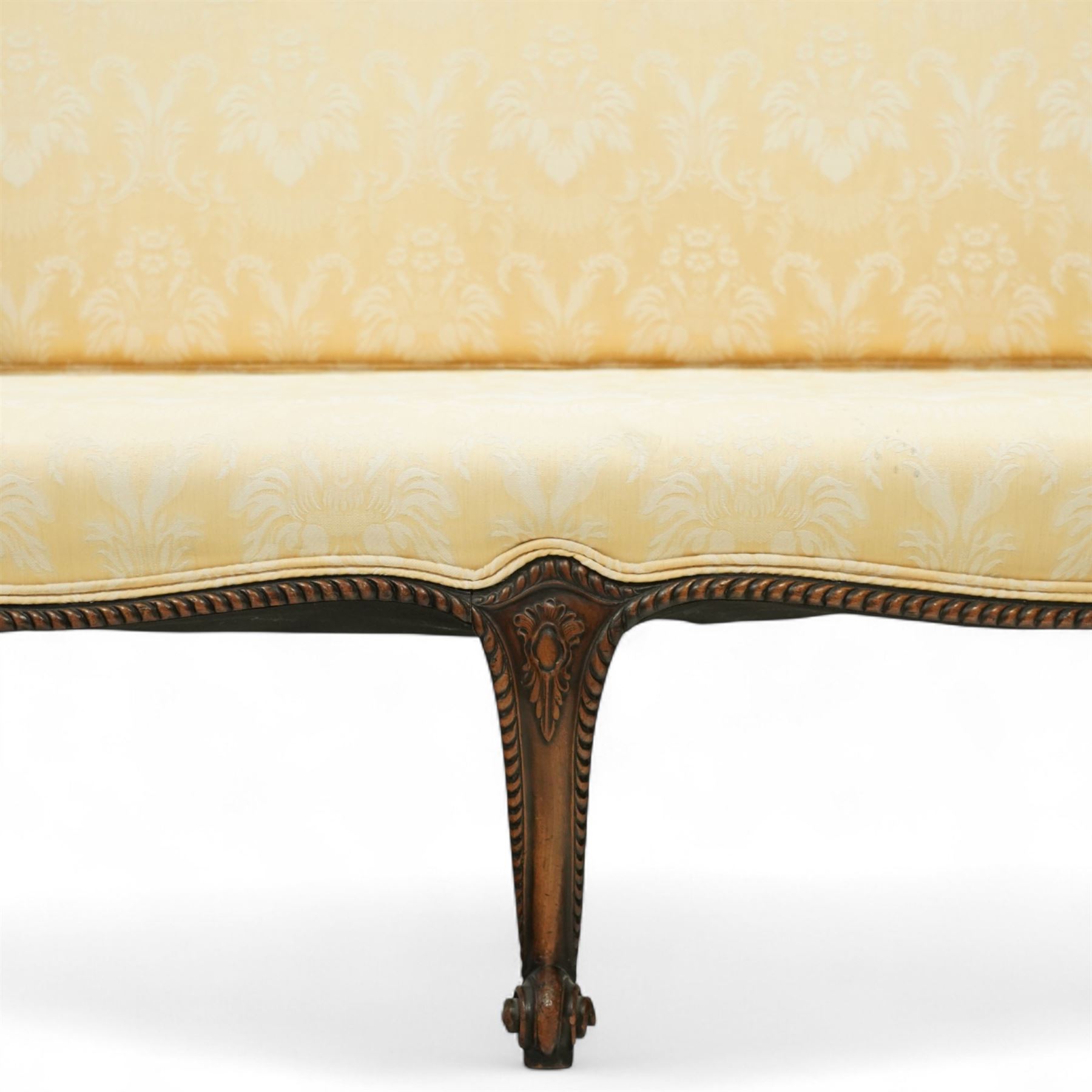 Early 20th century mahogany settee in the George III style, upholstered in pale yellow damask fabric, moulded serpentine seat rail with carved foliate detail, on cabriole supports with acanthus carved knees and scroll feet