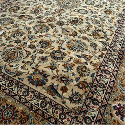 Kashan Persian rug, hand knotted, ivory ground rug, the rosette medallion decorated with projecting palmettes, on a field of swirling leafy branches and decorated with further palmettes, the scrolling border with repeating stylised plant motifs, within floral pattern guard stripes