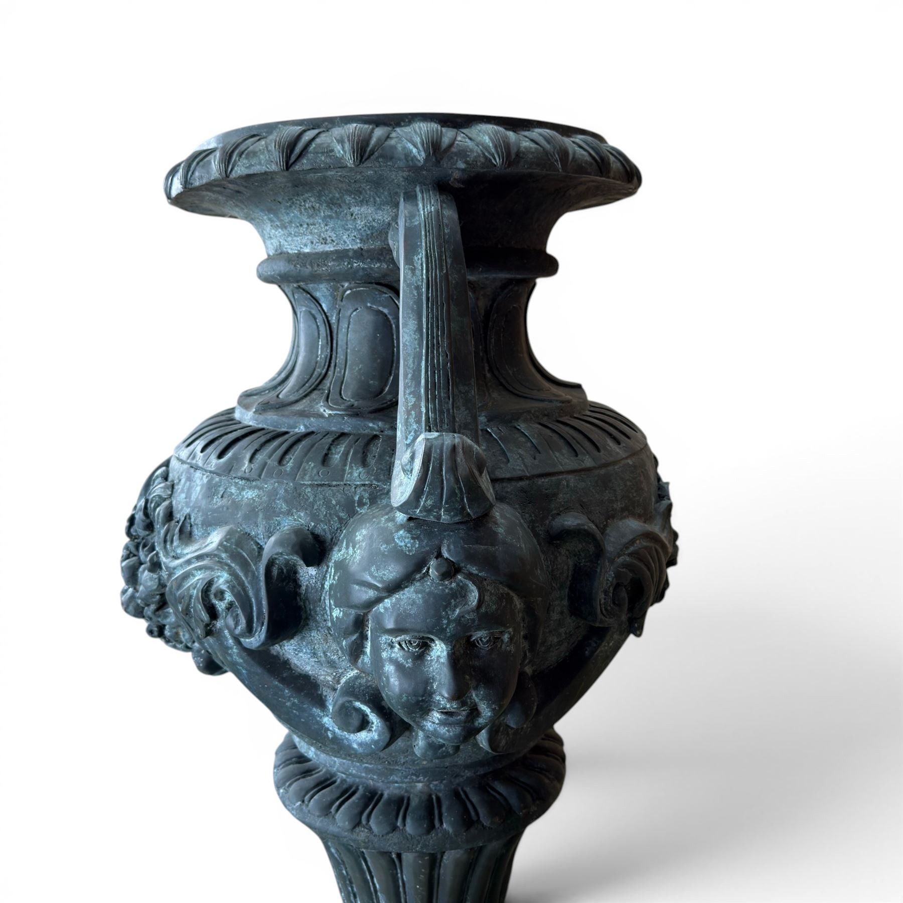 Large impressive Classical cast bronze center-piece urn, twin scroll handles with grape garlands, cherub masks and relief detail, raised on a circular cast stone pedestal with moulded detail