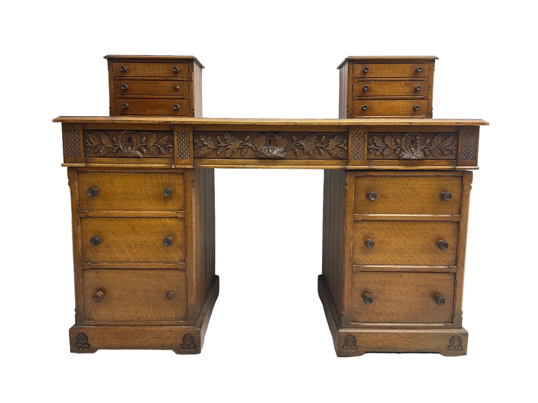 Late 19th century heavily carved oak twin pedestal desk, rectangular top with two raised trinket or correspondence structures each with three drawers, rectangular top over three frieze drawers carved with acorn and oak leaf decoration, each pedestal with three drawers with acorn husk shaped handles