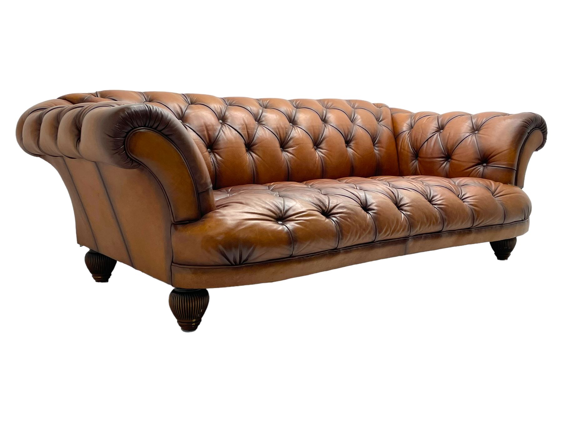 Tetrad - 'Oskar' grande three-seat sofa, Chesterfield shape with rolled arms, upholstered in buttoned tan leather, on turned and reed moulded feet 