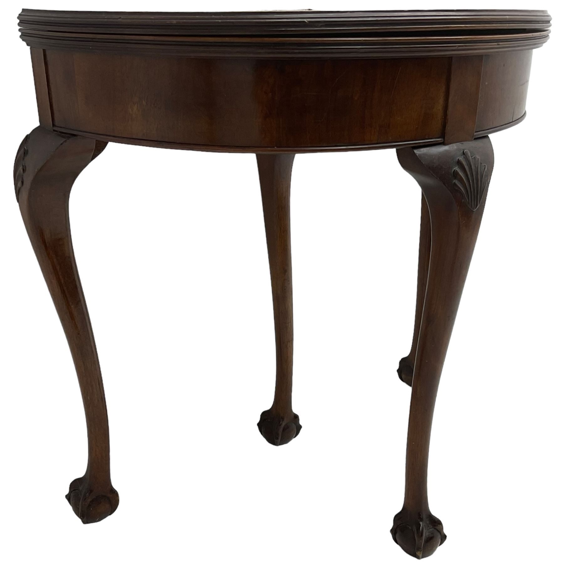 Early 20th century figured walnut demi-lune card table, fold-over reed moulded top with baize lined interior, pull-out rear support with storage well, on shell carved cabriole supports with ball and claw feet