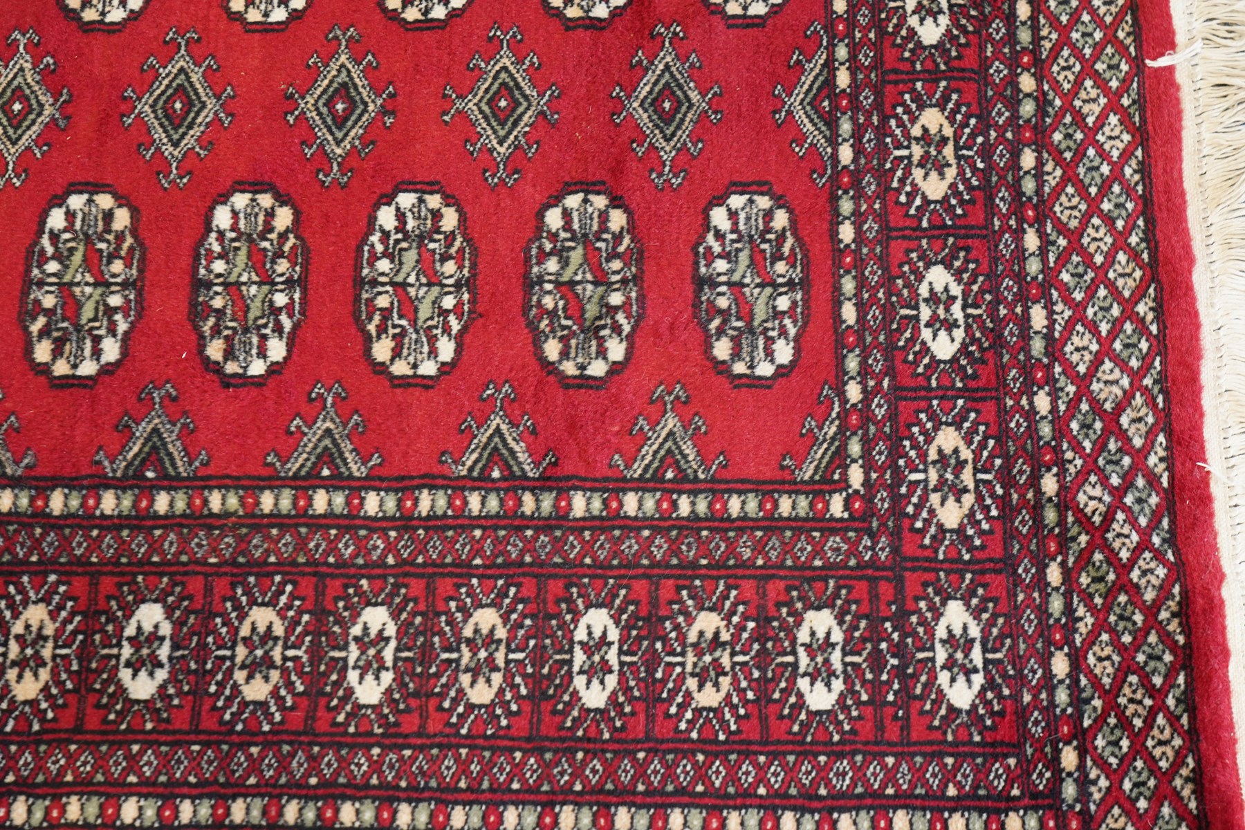 Two Afghan Bokhara crimson ground rugs, the fields decorated with repeating Gul motifs with geometric guard bands (126x190 & 157x250)