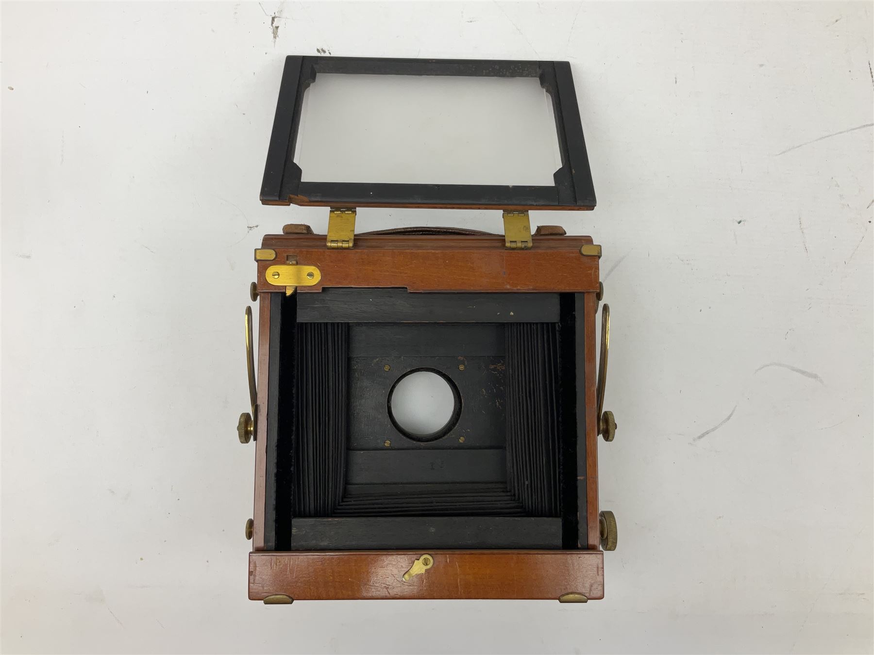 Ensign 'The Sanderson' folding plate camera in mahogany and lacquered brass, field model with canvas wrapped box, two mahogany photographic plates, 'Busch rapid Symmetrical F:8' lens,  and a wooden tripod 