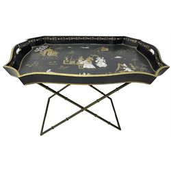 19th century design Chinoiserie style lacquered tray, painted with traditional scenes with figures and pagodas with gilt detail, on a folding simulated bamboo metal stand
