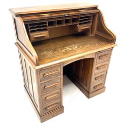 Early 20th century oak twin pedestal shaped tambour roll top desk enclosing fitted interior, two slides, seven graduating 
