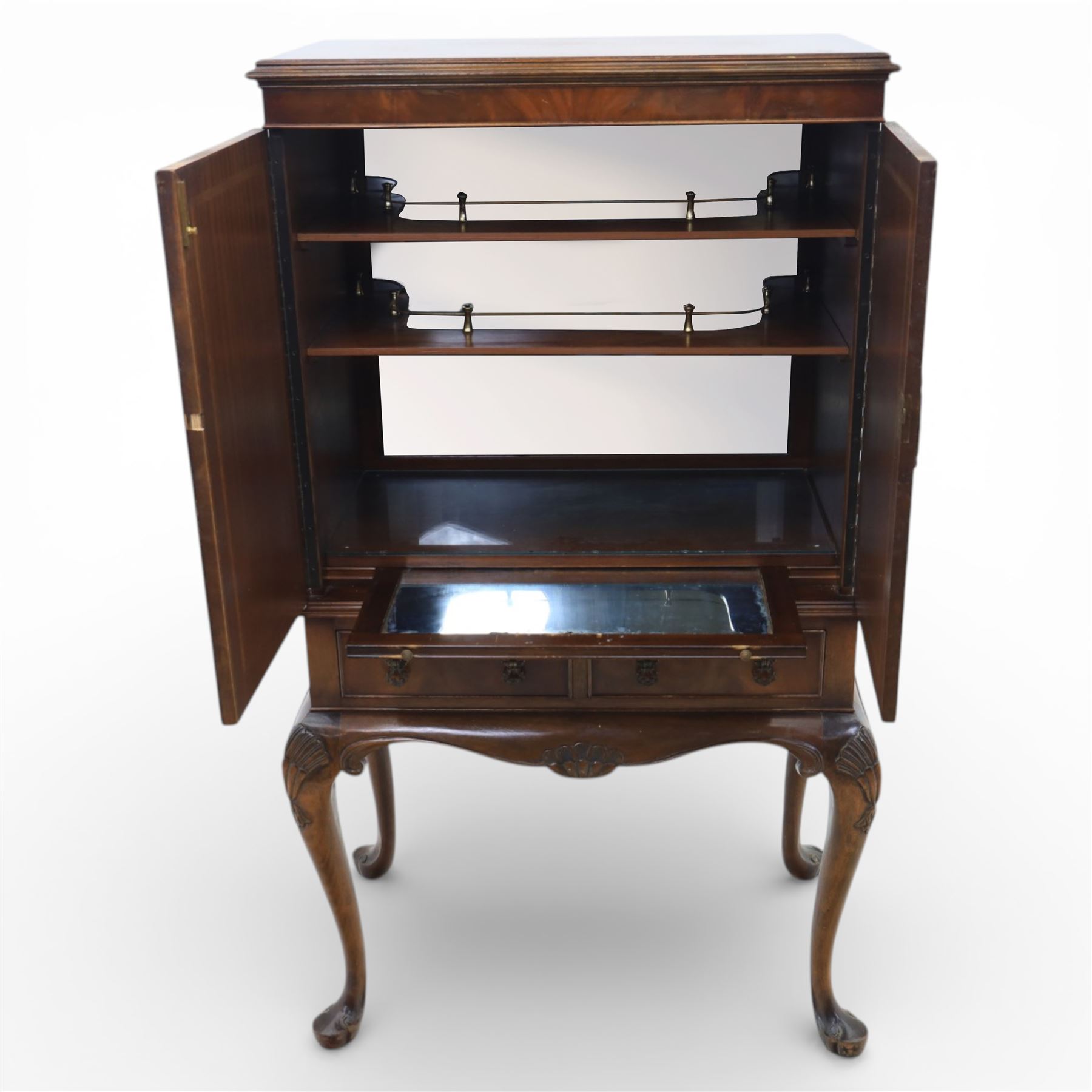 20th century Queen Anne style mahogany cocktail cabinet, moulded cornice above a pair of fielded panel doors with decorative strap hinges and central escutcheon, opening to a mirrored interior fitted with tiered shelves with brass gallery rails, pull-out glass inset mixing slide above three short drawers, shaped apron on cabriole supports with carved shell knees terminating in pad feet