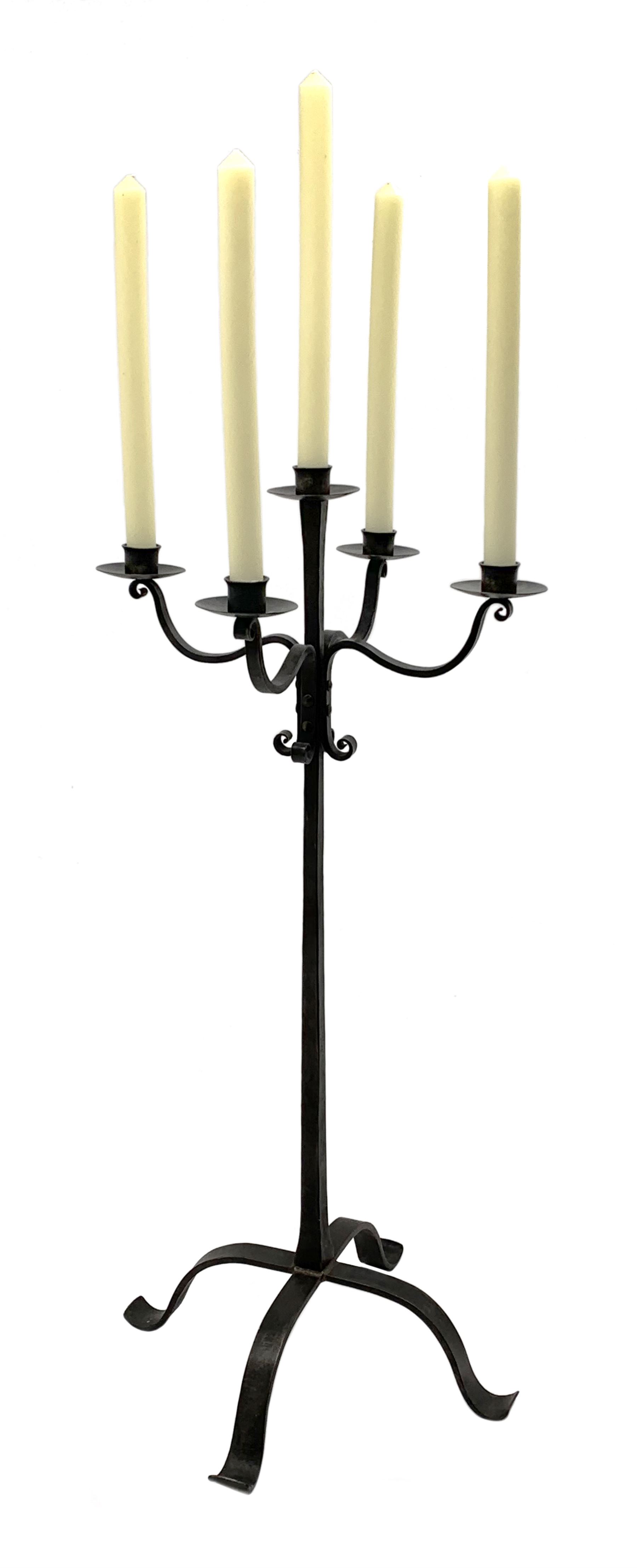 Wrought hand forged iron candle stand, four scrolled branches and central vertical branch with sconces, tapered column on four shaped and out splayed supports