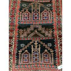 Baluchi dark indigo and crimson ground rug, decorated with cityscape within geometric border 