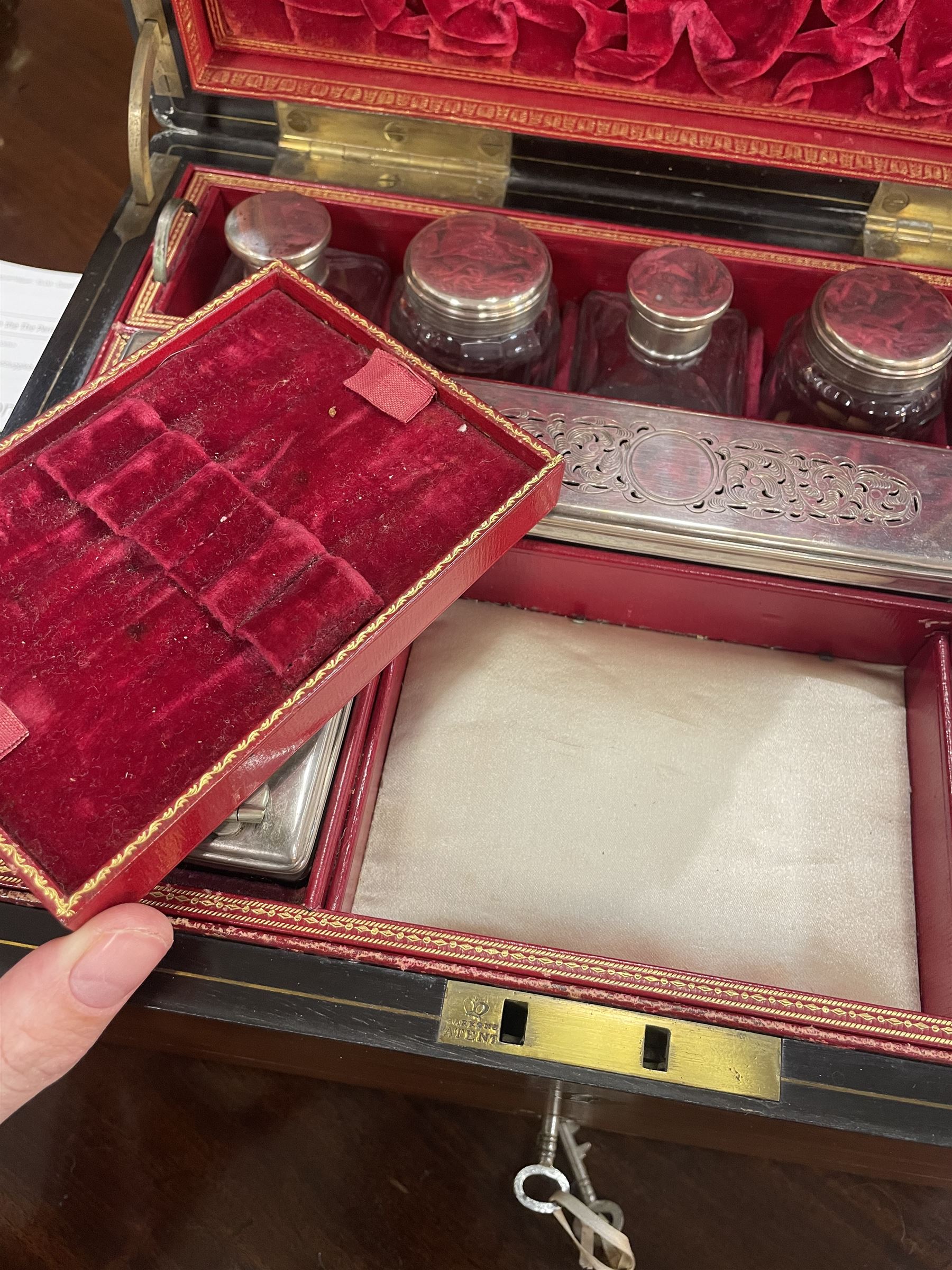  Victorian brass inlaid rosewood dressing table box, retailed by F.L. Hausburg, Liverpool, the lid centred by a brass cartouche, opening to reveal letter store to lid underside, above a fitted interior, with ten mounted cut glass jars, bottles and manicure set, within lift out leather trays, above jewellery drawer, with key, H17cm D24cm
