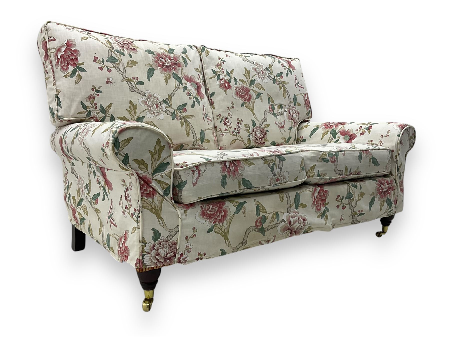 Steed Upholstery - 'Knightsbridge' two seater sofa, upholstered in cream fabric with pink and green floral design, loose back and seat cushions, raised on mahogany supports with brass castors