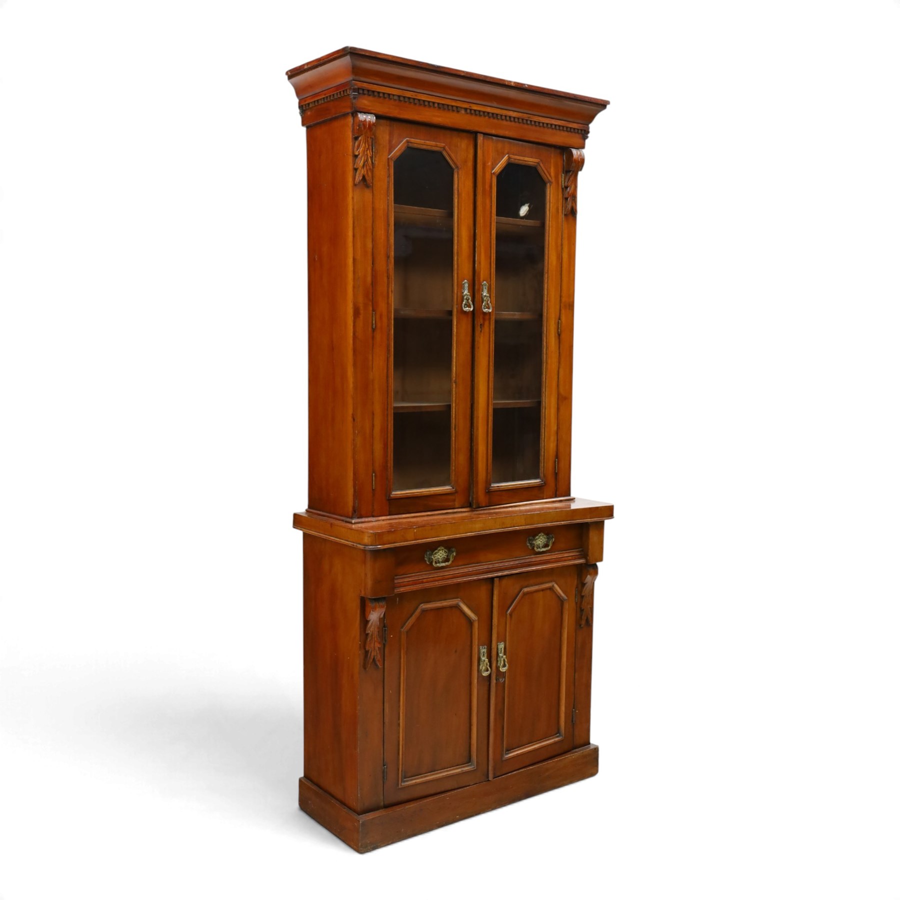 Victorian mahogany bookcase on cupboard of slender proportions, projecting cornice over dentil-frieze, fitted with twin-glazed doors enclosing three shelves, flanked by acanthus corbels, the base fitted with single frieze drawer over panelled cupboard, on skirted base