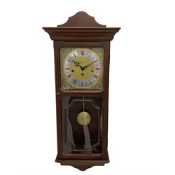 A 20th century wall clock in a simulated mahogany case with a two-part glazed door, brass dial with roman numerals on a silvered chapter ring, brass spandrels, pierced steel hands and visible pendulum, three train Metamec 8-day movement with Westminster chimes sounding on gong rods.

