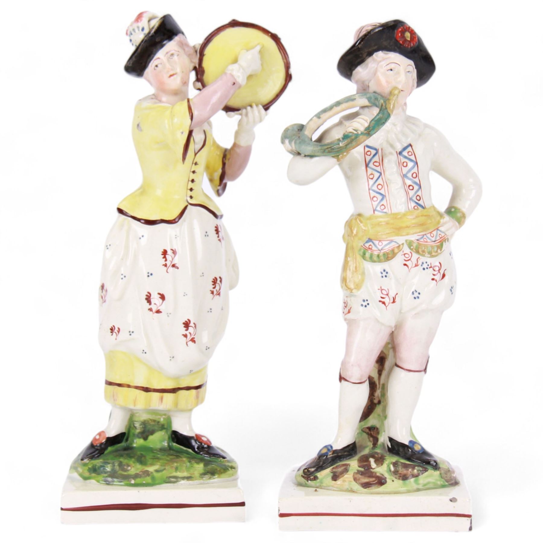 Pair of early 19th century Staffordshire pearlware figures, modelled as musicians, he playing the French horn, she the tambourine, each upon square plinth, tallest example H23cm