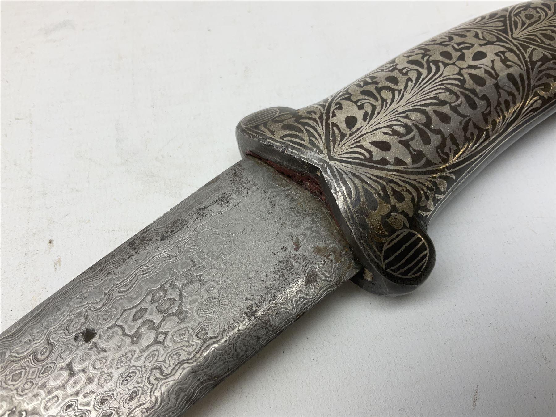 Indian Khanjar dagger with 28cm curving damascus steel blade inlaid with silver floral emblem, white metal and niello style grip in the form of a bird's head with pronounced beak and matching scabbard L44cm overall