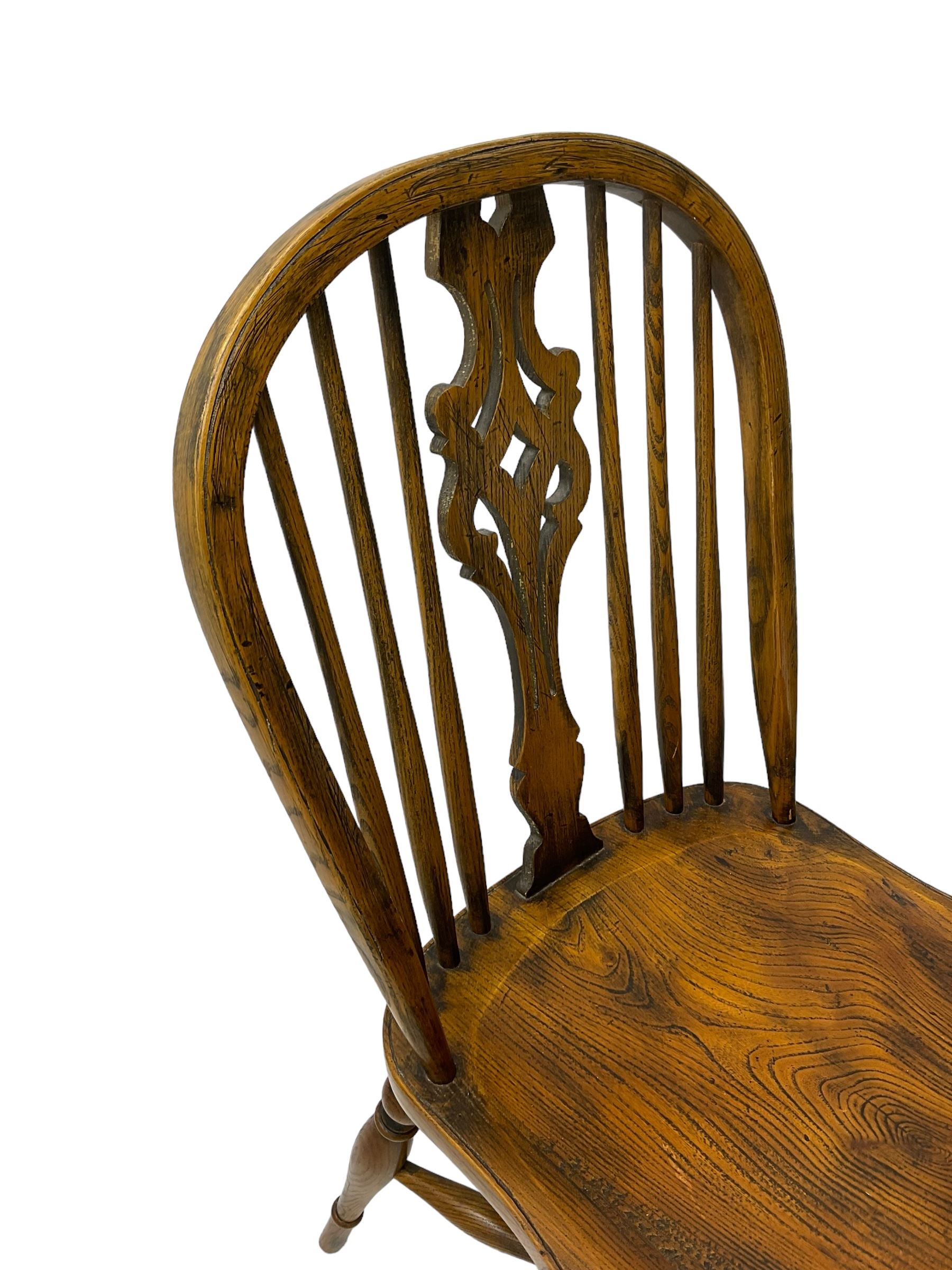 Set of four elm Windsor dining chairs, high hoop and stick back with shaped pierced splat, over shaped saddle seat, raised on ring turned supports joined by crinoline stretcher