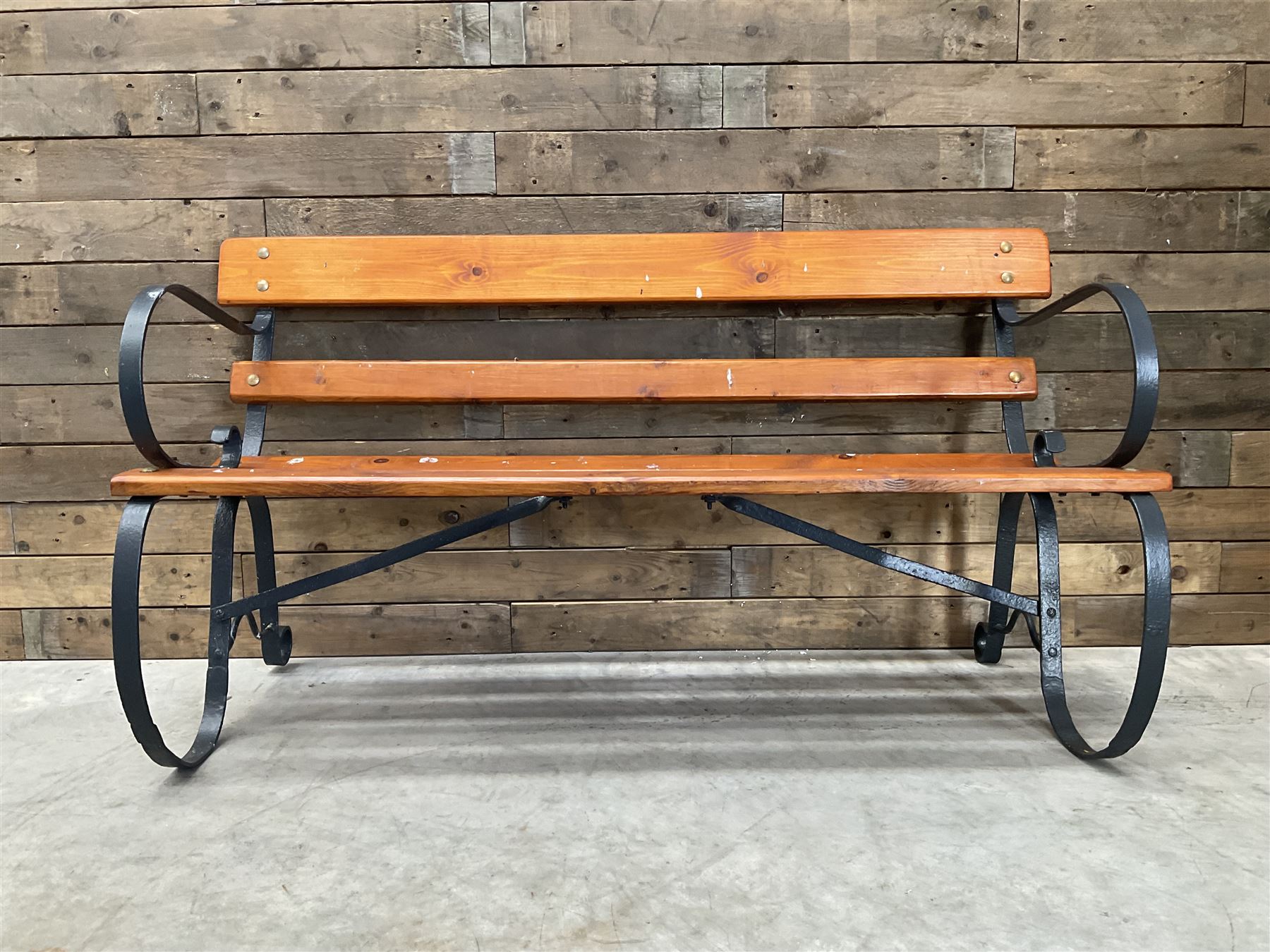 Wrought metal scrollwork and wood slatted garden bench