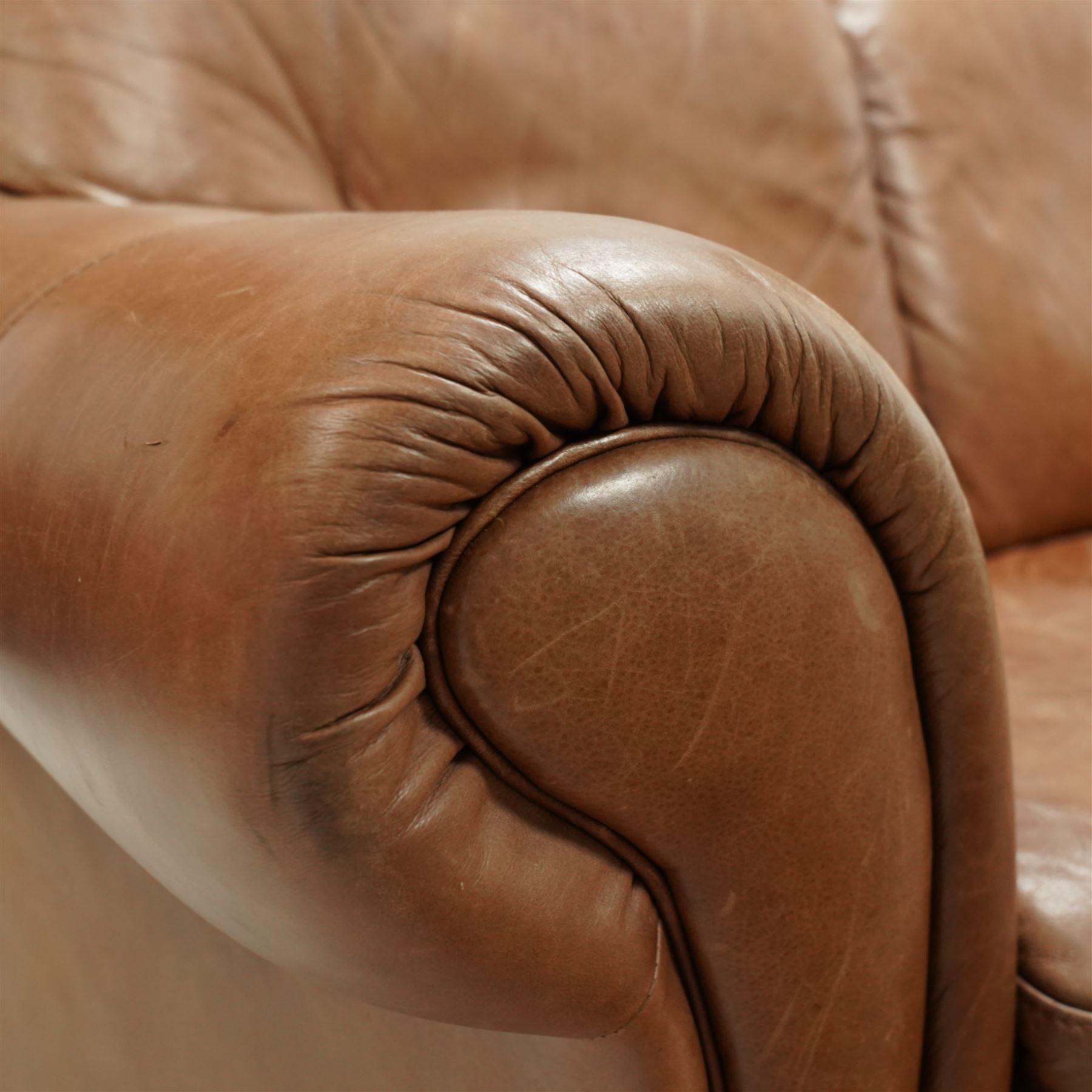 Two-seat hardwood-framed sofa, traditional shape with rolled arms, upholstered in tan leather, on block feet